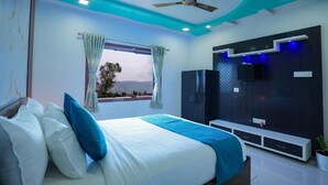 Un dormitorio moderno con una cama grande, ventilador de techo, televisor montado en la pared y ventana con cortinas.