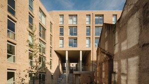 Een modern gebouw met een bakstenen gevel, meerdere ramen en een centrale ingang met treden.