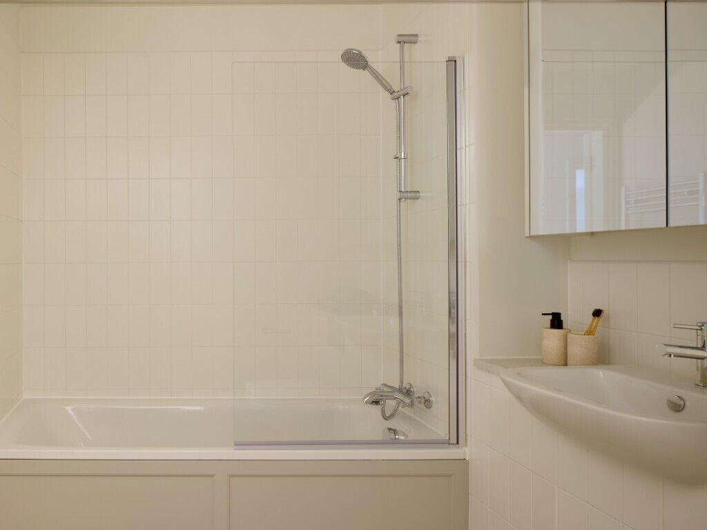 A modern bathroom with a glass-enclosed shower, a standalone bathtub, and a sink with toiletries.