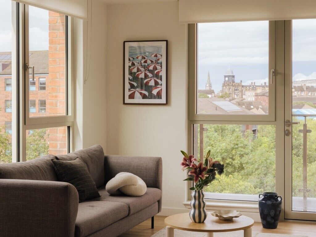 A living room with a sofa, a vase with flowers, and a painting on the wall.