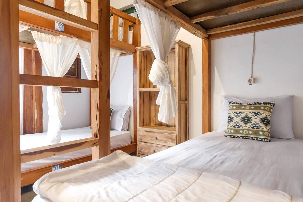 Una habitación rústica de madera con literas, una cama individual y una silla colgante.
