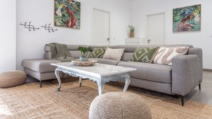 Ein modernes Wohnzimmer mit grauem Sofa, einem weißen Couchtisch und zwei an der Wand befestigten Kunstwerken.