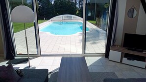 Une pièce dotée d’une porte vitrée donnant sur une piscine, d’un téléviseur et d’un canapé.