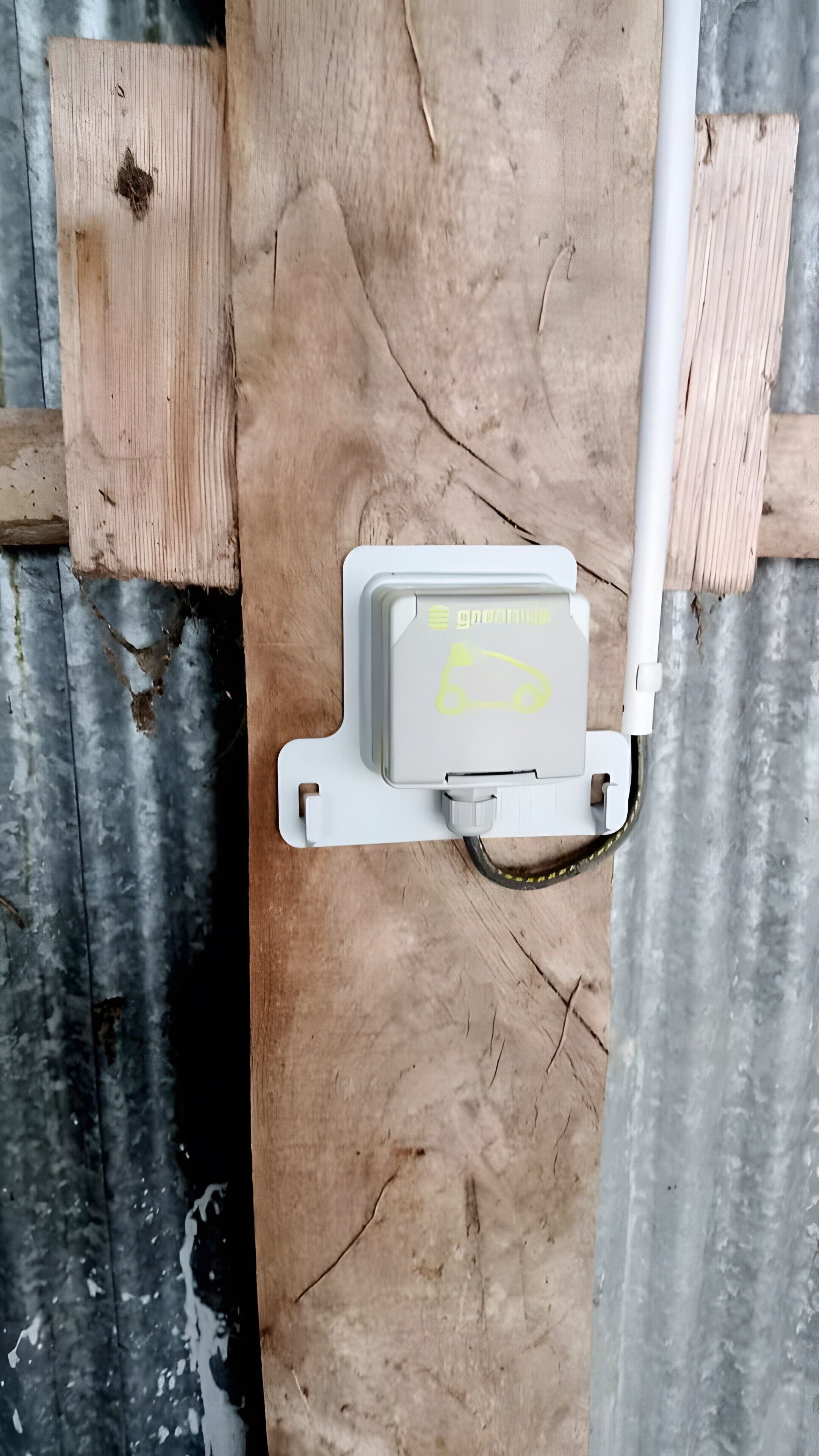 Un quadro elettrico con un simbolo giallo, fissato a una struttura di legno con evidenti crepe.