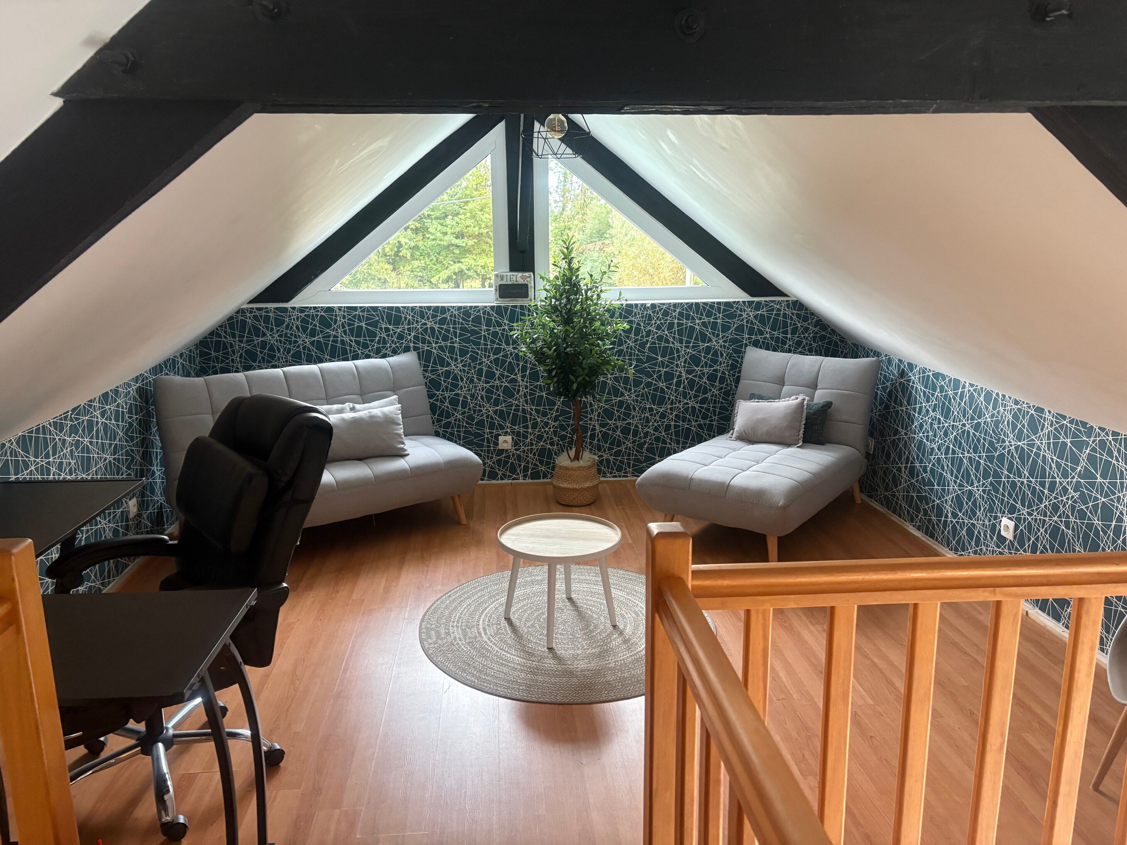 Una habitación acogedora con sofá, sillón, mesita y una planta en maceta.