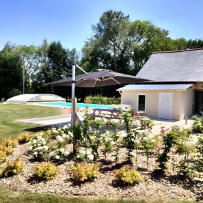 Un jardin avec une piscine, des meubles de patio et un espace abrité avec un parasol.