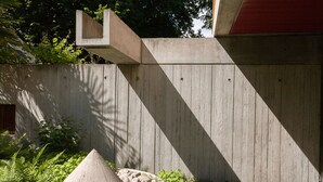 Een betonnen muur met een geometrisch uitgesneden gedeelte en een stenen constructie.