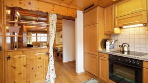 Een houten cabin interieur met een keukenhoek, voorzien van houten kastjes, een fornuis en een waterkoker.