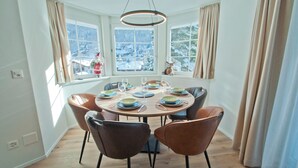 A dining area with a round table set for four, surrounded by six chairs. - Chalet Aeschhorn, Apartment Lucy (Zermatt)