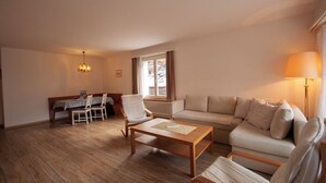Ein gemütliches Wohnzimmer mit Sofa, Couchtisch und einem Essbereich mit Tisch und Stühlen.