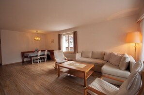 Un salon spacieux comprenant un canapé, des fauteuils, une table basse et un coin repas avec une table et des chaises.