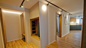 A modern apartment with a wooden floor, built-in closet, and a kitchen in the background. - Chalet Aeschhorn, Apartment Edward (Zermatt)