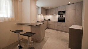 Una cocina moderna con una isla central, dos taburetes de bar y electrodomésticos integrados.