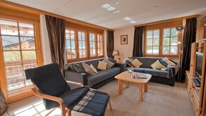 Een woonkamer met een bank, stoelen, een salontafel en een televisie.