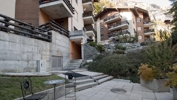 A courtyard with outdoor seating, a staircase, and a view of a mountain. - Haus Bodmen C, Apartment Edelweiss (Zermatt)