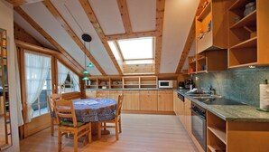 Eine kleine Küche mit Holzausstattung, einem Esstisch mit Stühlen und einem Oberlicht.