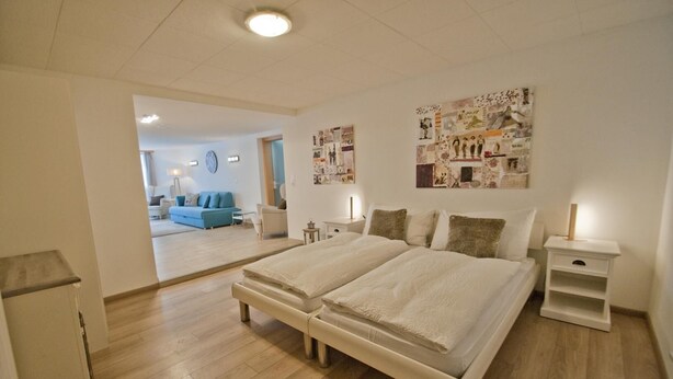 Quarto com cama de casal, mesas de cabeceira e parede decorada com diversas imagens.