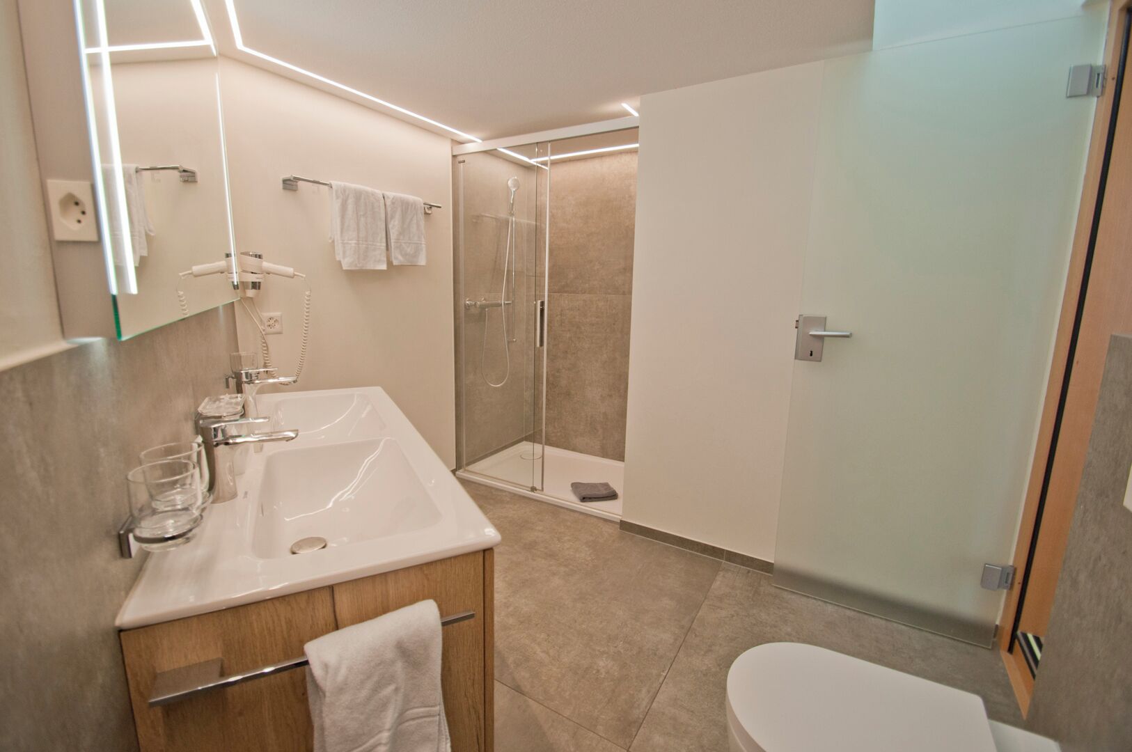 Ein modernes Badezimmer mit einer Duschkabine, einem weißen Waschbecken und einer Toilette.