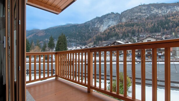 A balcony with a wooden railing overlooking a parking area and a mountainous landscape. - Zardin 7 (Valdidentro)
