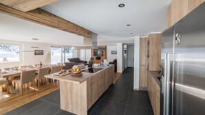 A modern kitchen with a central island, wooden cabinets, and a stainless steel refrigerator. - Haus Andy, Apartment Andy (Zermatt)