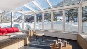 A modern interior with a large glass wall offering a snowy mountain view. - Haus Andy, Apartment Andy (Zermatt)