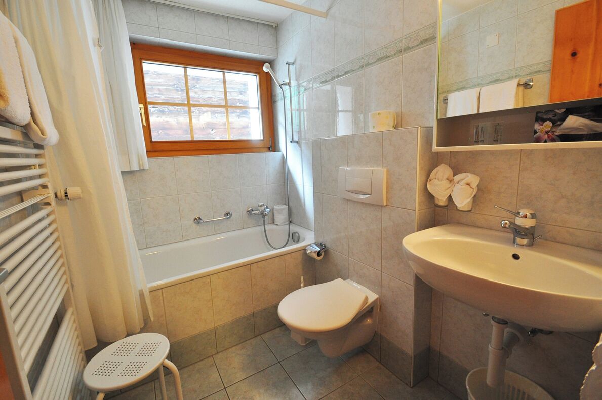 Un baño con bañera, inodoro, lavamanos y ventana.