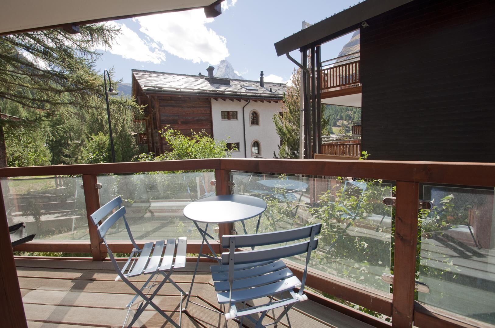 Ein Balkon mit Tisch und Stühlen, mit Blick auf einen Berg und ein Gebäude.
