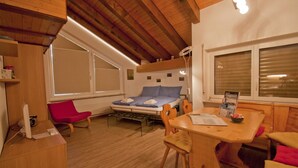 Ein gemütliches Zimmer mit einem Bett, einem Esstisch und einem roten Sessel.