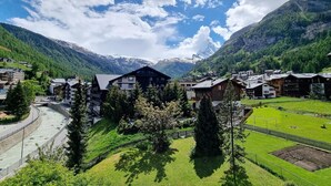 A mountain village with traditional wooden houses, a winding road, and a river. - Haus Matten, Studio Findeln (Zermatt)