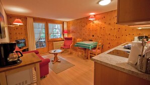 Ein gemütliches Zimmer mit Holzvertäfelung, einem Esstisch mit Stühlen, einer Kaffeemaschine und einem kleinen Fernseher.