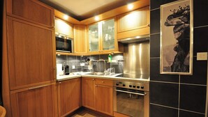 Uma cozinha moderna com armários de madeira, eletrodomésticos de aço inoxidável e paredes com azulejos pretos.