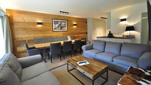 Uma sala de estar moderna com um sofá, uma mesa de centro e um espaço de refeições com cadeiras e uma mesa.