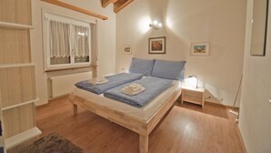 Une chambre à coucher avec un lit en bois, une table de chevet avec une lampe, une fenêtre avec des rideaux et un plafond en bois.