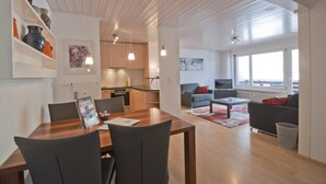 A modern apartment with a dining area, kitchen, living room, and a balcony with a view. - Haus Arola, Apartment Hirle (Zermatt)