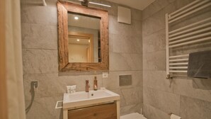 A modern bathroom with a wooden-framed mirror, a white sink, and a toilet. - Haus Aosta, Studio Aosta (Zermatt)