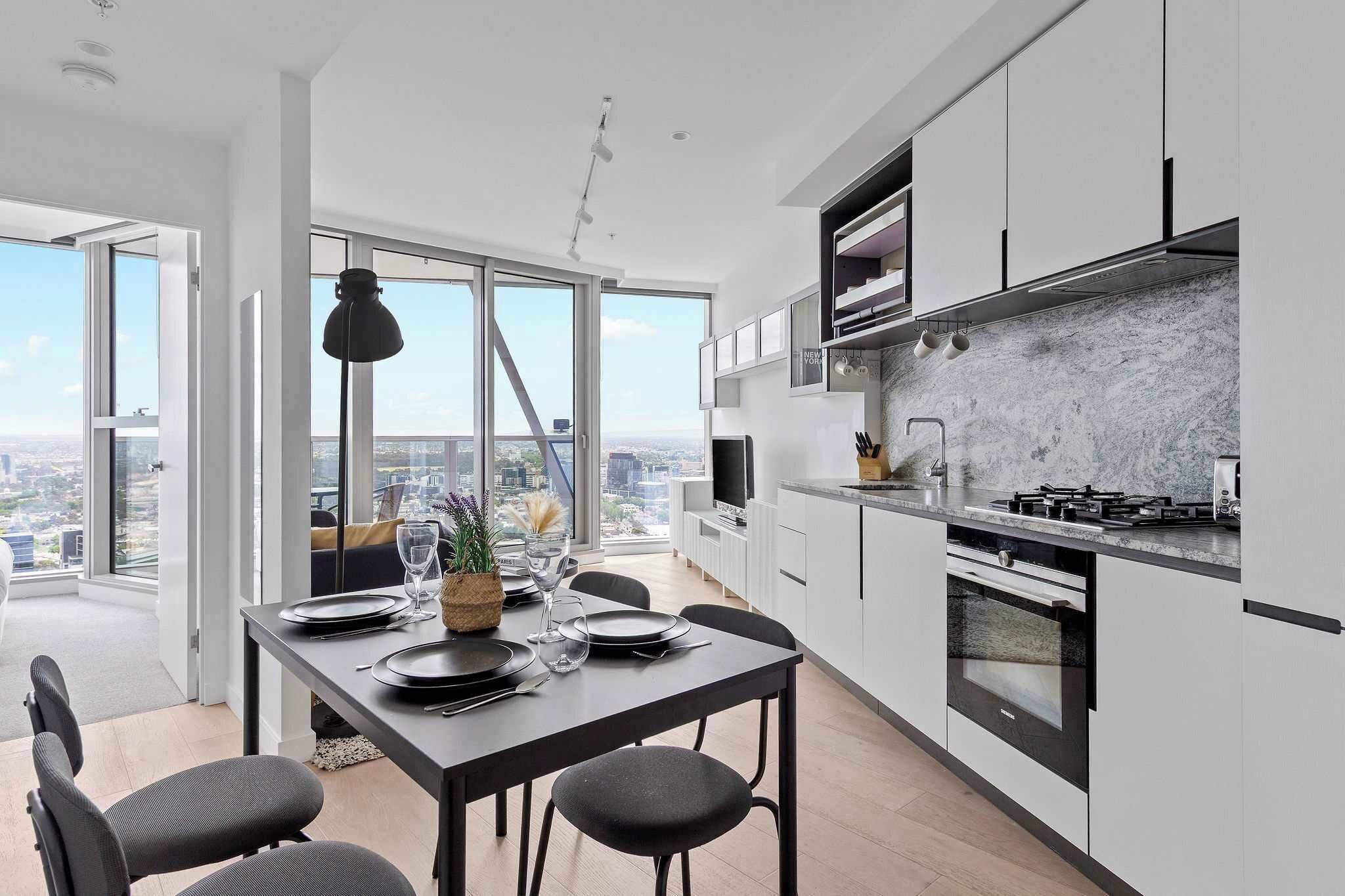 A modern kitchen with a large island, built-in appliances, and a view of the city.