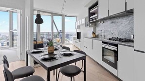 A modern kitchen with a large island, built-in appliances, and a view of the city. - Cozy Apt Next to Southern Cross With Amazing Views (Melbourne)