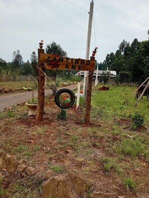 Un letrero de madera rústico con el texto "CANTINHO DA ANE" en un entorno rural.