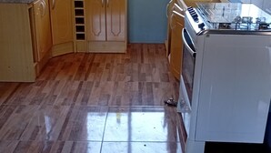 Une cuisine avec des meubles de rangement en bois, une cuisinière et une fenêtre.