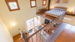 A multi-level bedroom with a wooden staircase, a bed, a fireplace, and a balcony with outdoor furniture. - Charming villa in Crestatx, near Pollensa (Sa Pobla)