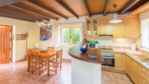 A kitchen with wooden cabinets, a dining table with chairs, a microwave, and an oven. - Charming villa in Crestatx, near Pollensa (Sa Pobla)