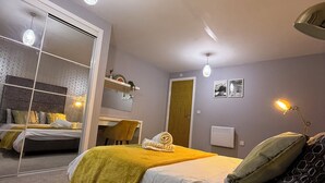 Une chambre moderne avec un grand lit, un miroir, un bureau et une chaise.