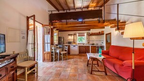 Un accogliente soggiorno con un divano rosso, arredi in legno, un tavolo da pranzo e un angolo cottura sullo sfondo.