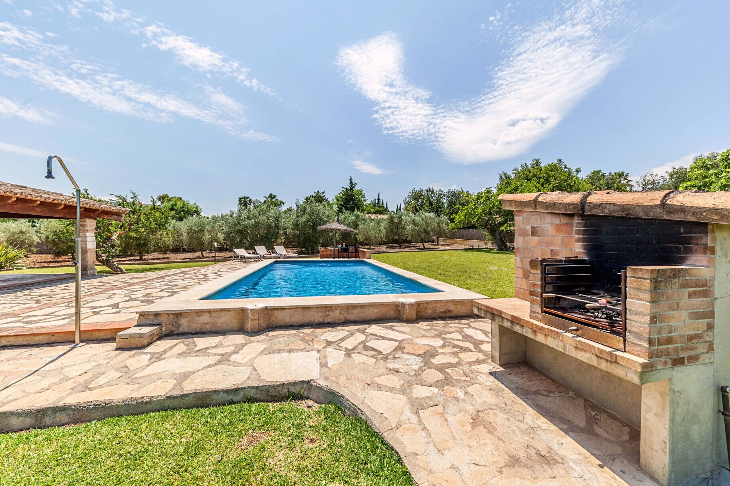 A backyard with a swimming pool, a barbecue grill, and a pergola.