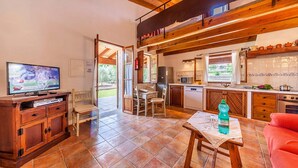 Un'ampia cucina con travi in legno, una zona pranzo con tavolo e sedie, e un televisore a sinistra.