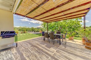 An outdoor patio with a covered seating area, a grill, and potted plants. - Beautiful villa with mountain views, 5km to beach (Alcúdia)