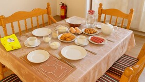 A dining table set with plates, bowls, and utensils, surrounded by wooden chairs.