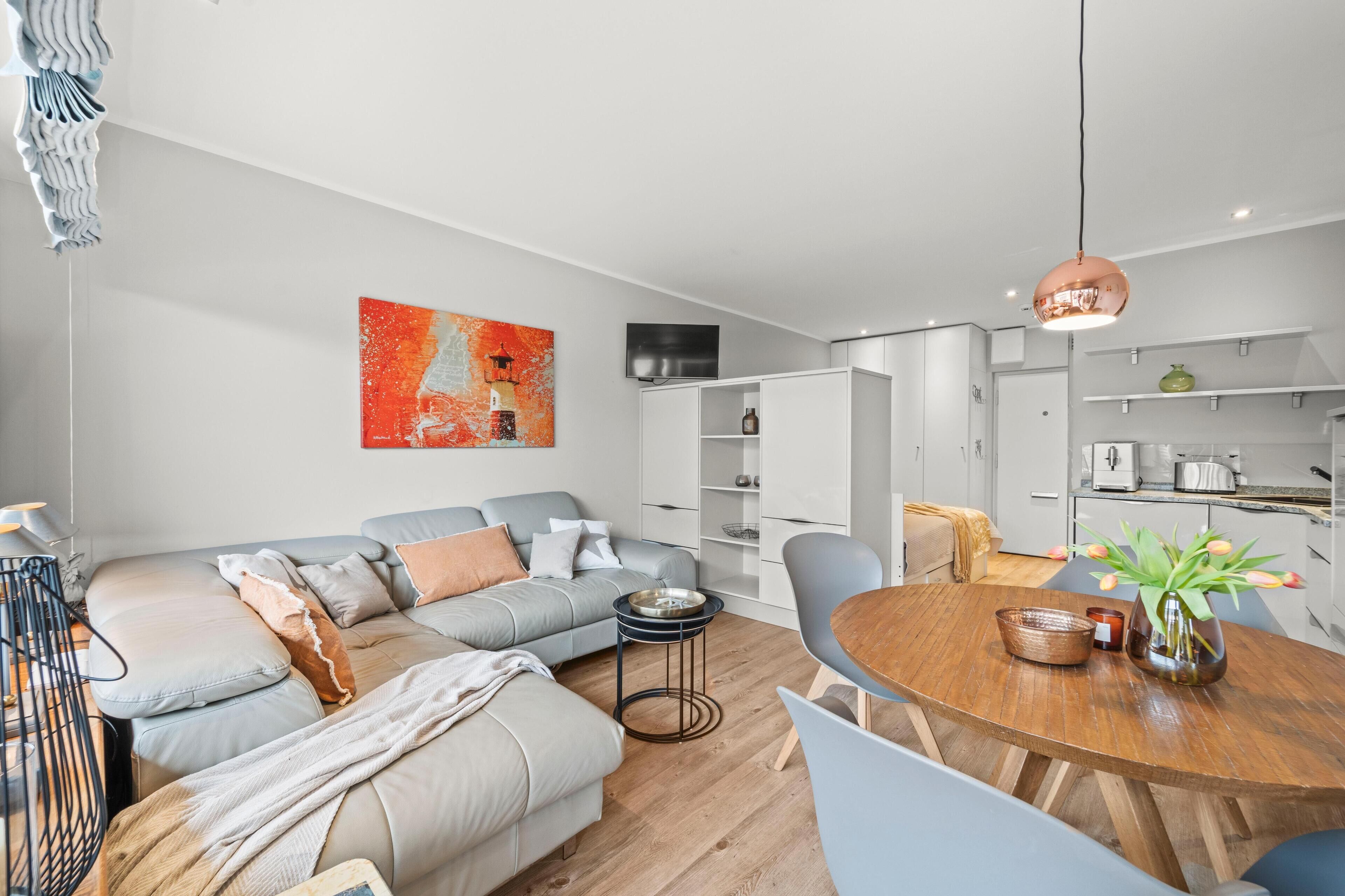 A modern living room with a sofa, coffee table, and a dining area with chairs.