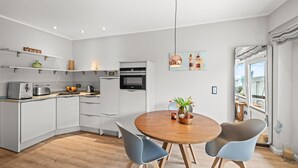 Una cocina moderna con armarios blancos, una mesa redonda de madera y dos sillas.