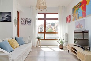 A modern living room with a sofa, TV, and large window. - Appartamento luminoso a San Pietro (Roma)